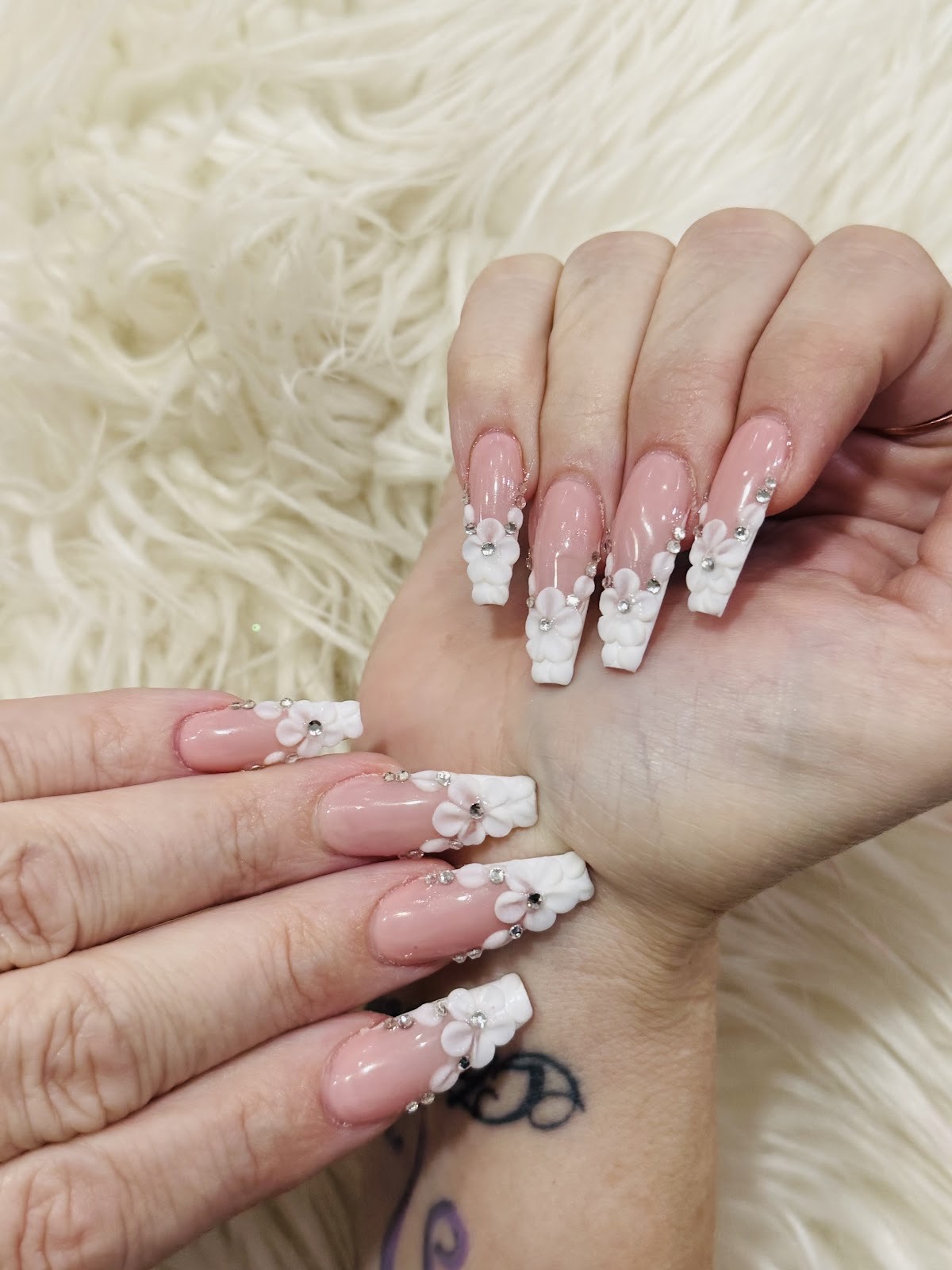 Elegant coffin-shaped nails with sculpted white 3D flowers and rhinestones at 5th Nail Lounge