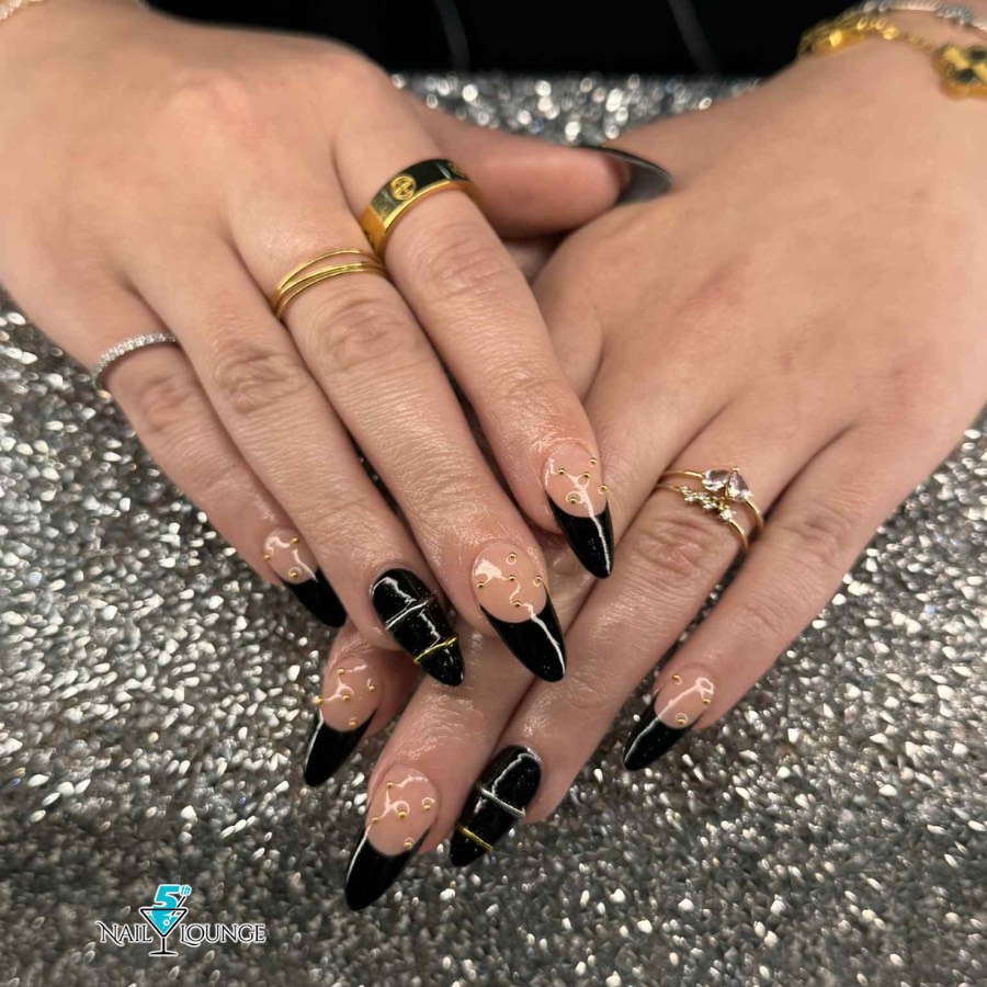 Black and nude stiletto nails with negative space line art and gold rings